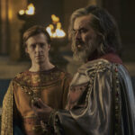 Kemen looking at his father, Ar-Pharazôn, who is looking at an ornate scepter he is holding.