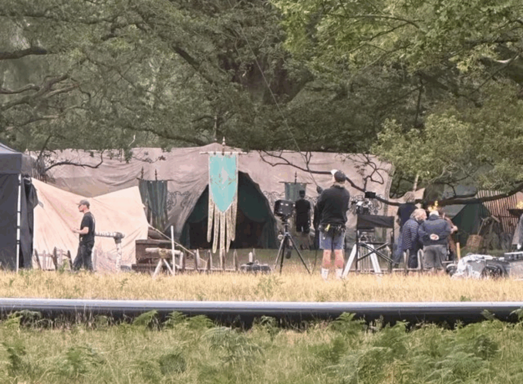 Location shoot in a forested area with suspiciously Elven-looking tents and a banner with Gil-galad's sigil. Filming crew scattered between.