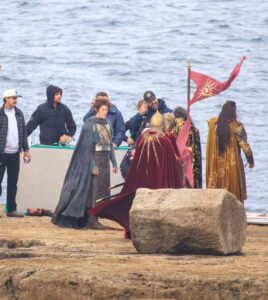 Gil-galad and Ar-Pharazôn standing on a rocky platform with an Elven guard and a Númenórean guard. Crew members are also standing around. The sea is visible in the background