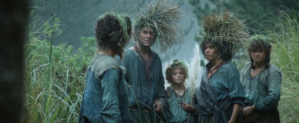 The Brandyfoot family and Poppy among vegetation, wearing camouflage headgear 