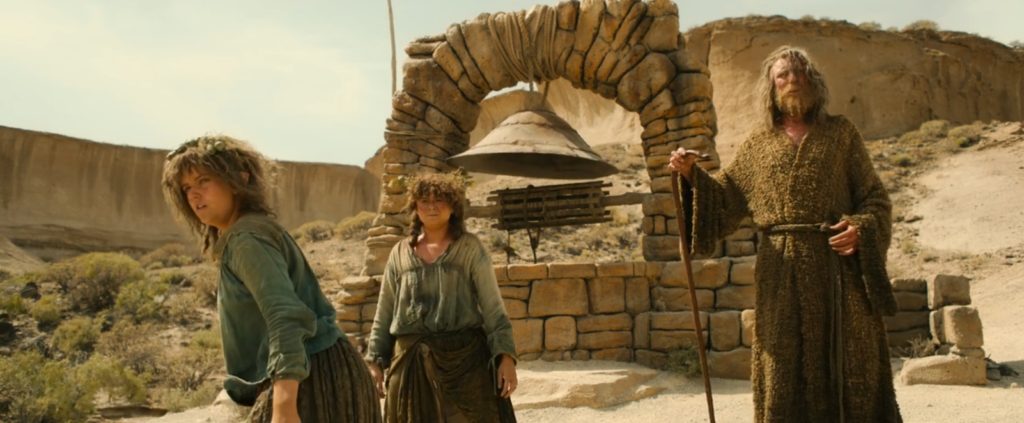 Nori, Poppy and the Stranger (aka Gandalf in the future) standing next to a well in Rhûn