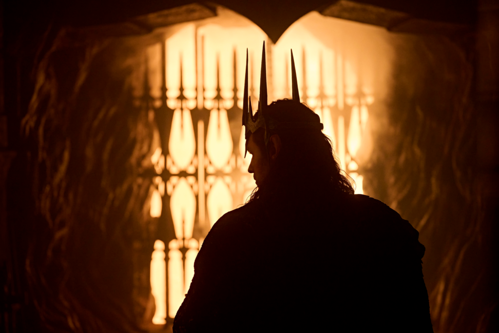Silhouette image of Sauron wearing Morgoth's crown in quarter profile. He appears to be in a tunnel and the light and the end looks fiery.