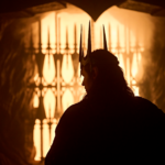 Silhouette image of Sauron wearing Morgoth's crown in quarter profile. He appears to be in a tunnel and the light and the end looks fiery.