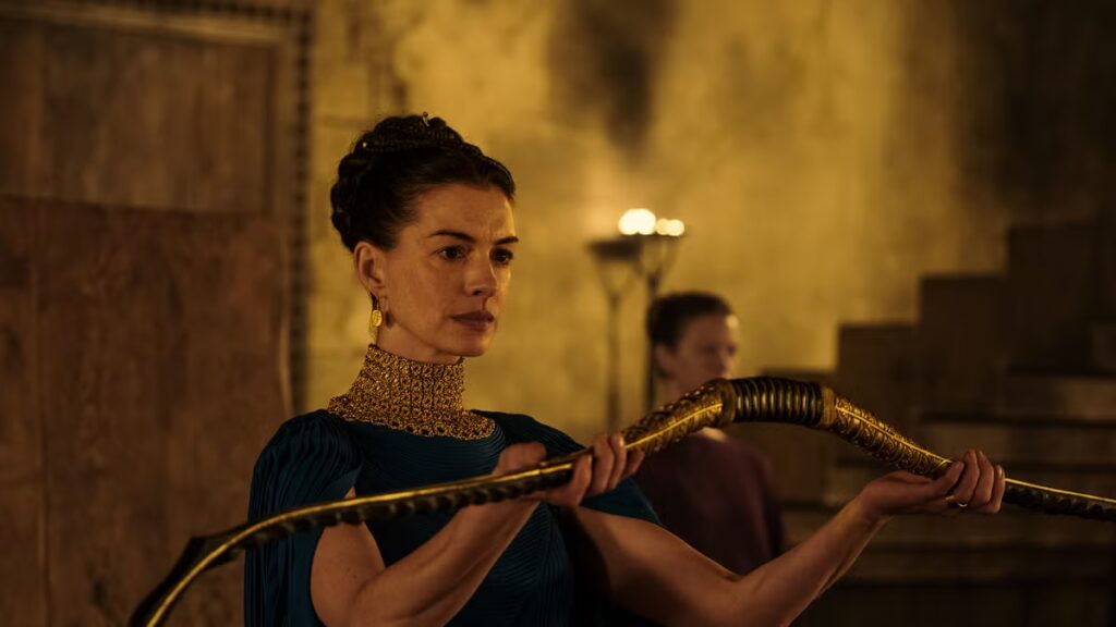 Anne Hathaway as Penelope in The Odyssey holds up Odysseus's bow as a test for the suitors