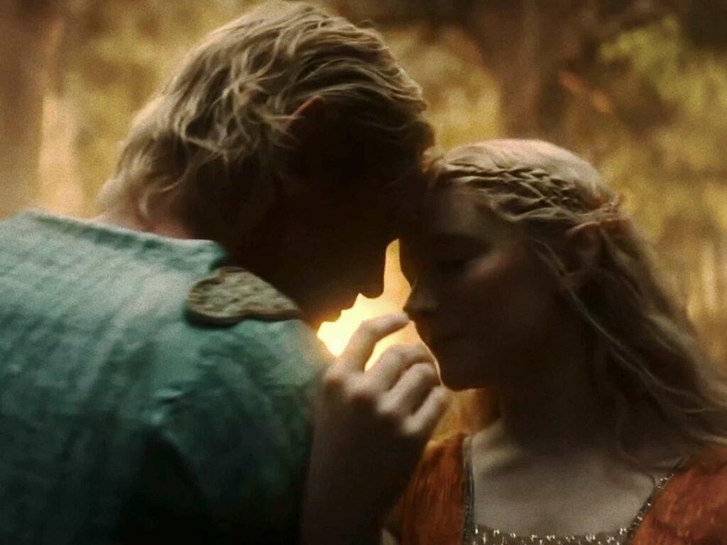 A close photo of Celeborn and Galadriel tenderly touching their foreheads together as they dance in a golden glade