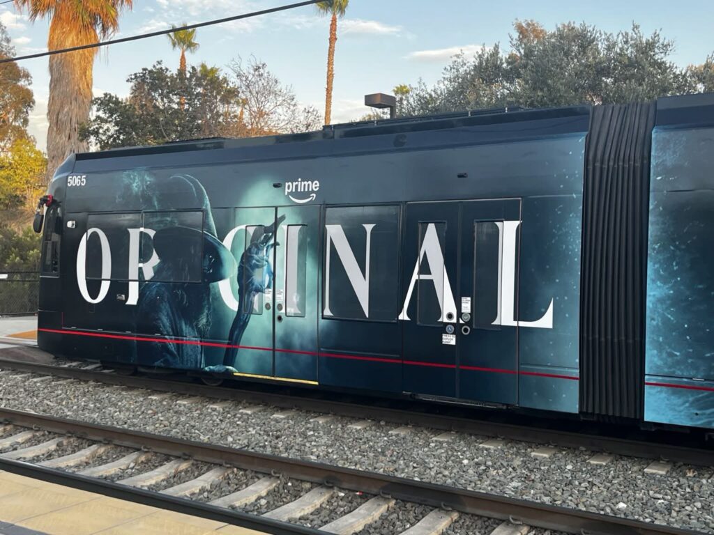 Photo of an ad on covering the whole outside a tram with the word "ORIGINAL", and a mostly backlit Gandalf with a pointy hat and staff (a "gand" in Season 2 parlance). The colour scheme is mostly dark with cool blue highlights