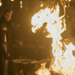 An orc screams as his hand burns, while Sauron looks on smirkingly behind