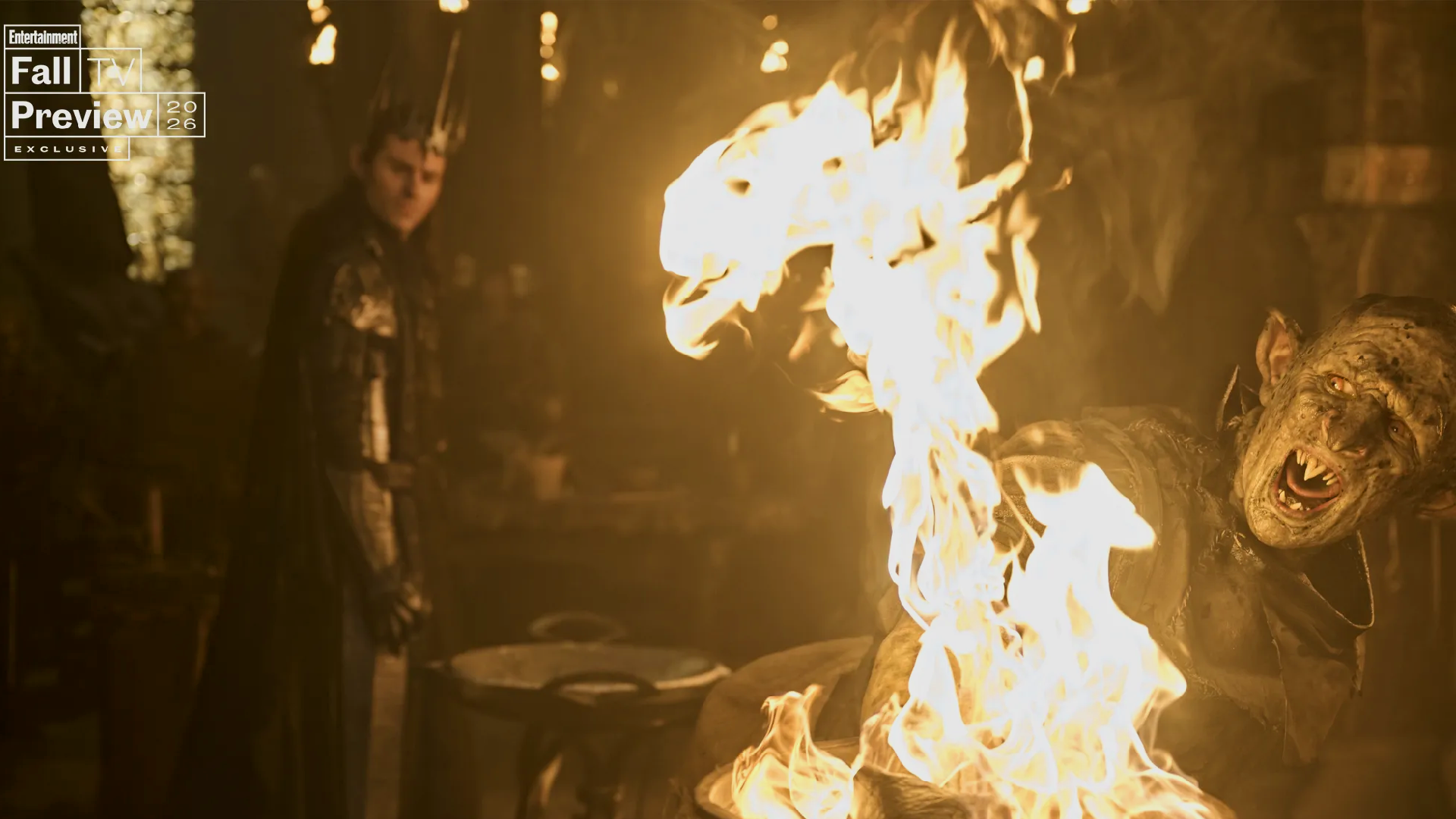 An orc screams as his hand burns, while Sauron looks on smirkingly behind