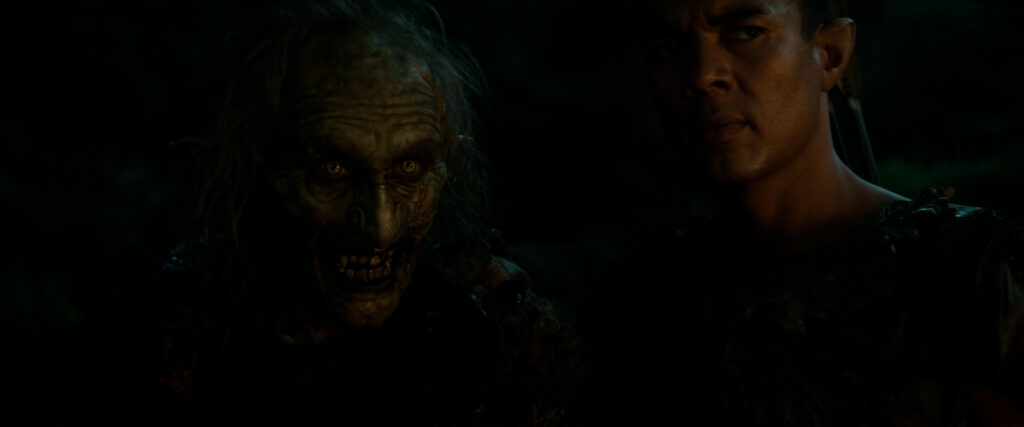 Marnûkh and Arondir standing together in a dark scene lit by firelight