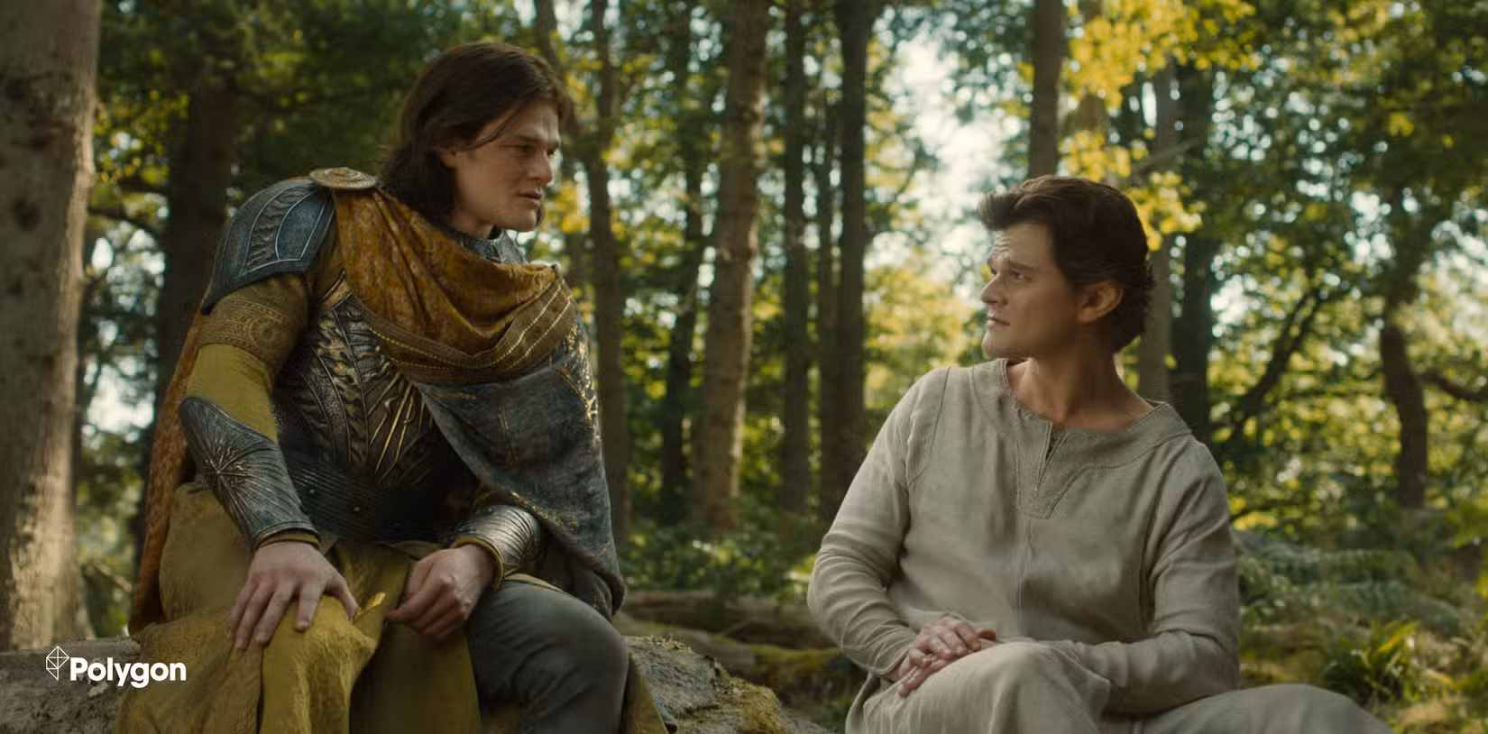 Elros wearing armour and Elrond wearing simple clothes having a discussion in a wood. Both are played by Robert Aramayo. Credits: Polygon
