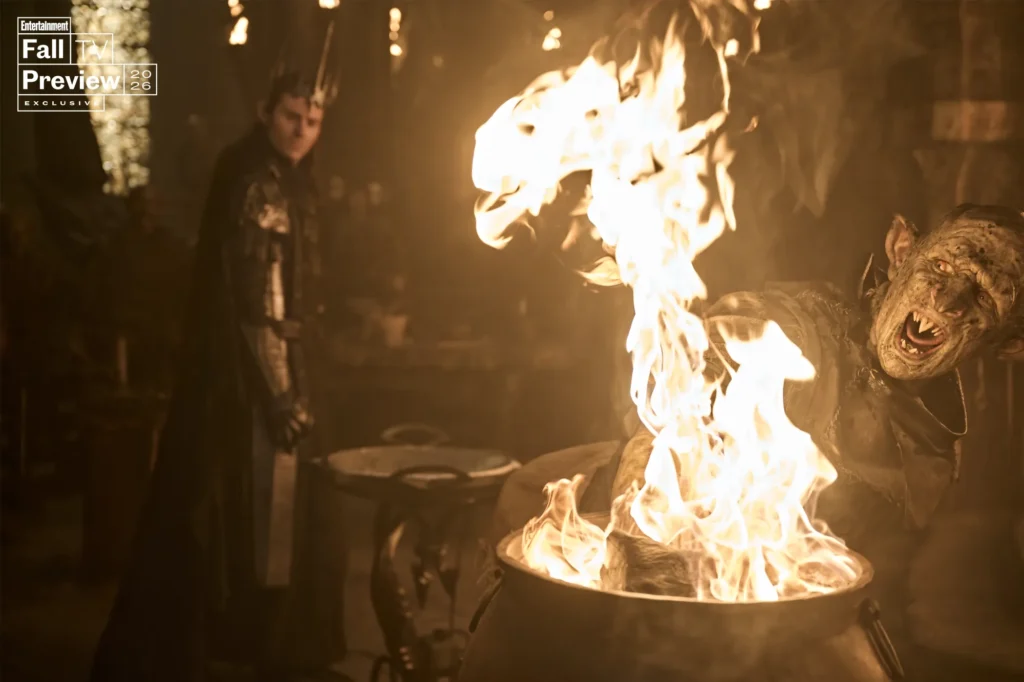 An orc screams as his hand burns, while Sauron looks on smirkingly behind