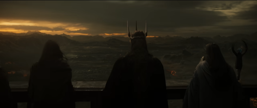 Shot looking out over the shoulders of three people (Sauron, the blue-robed Dark Wizard, and someone a bit like Gandalf) on a balcony, at a very large army in Mordor