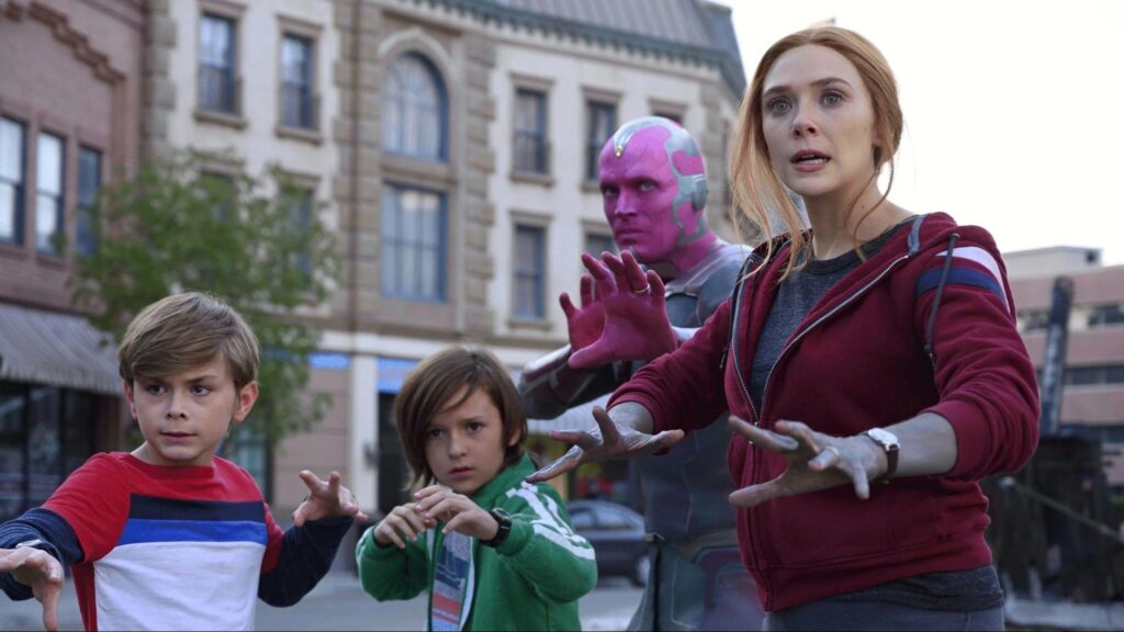Image of Wanda Maximoff, Vision (as an android) and their two boys (primary school aged), on a street, looking ready for magical action